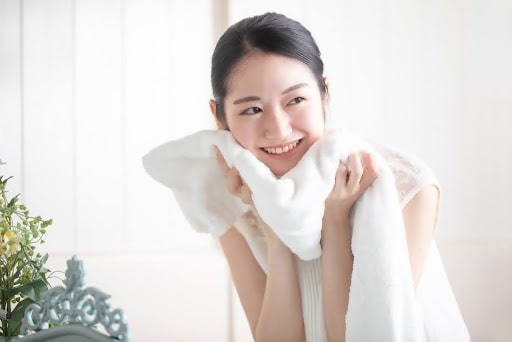 洗顔後に顔を拭く笑顔の女性