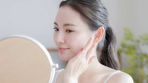 鏡を見て頬にふれる女性