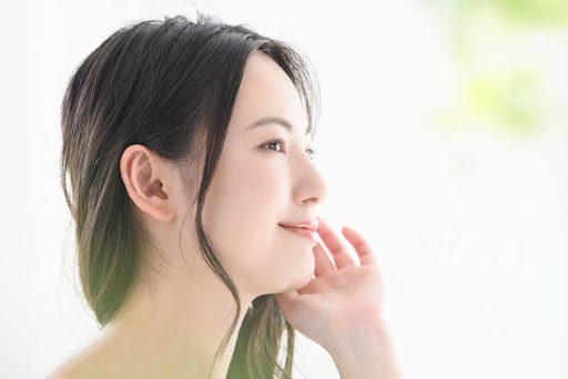 顎に手を当て微笑む女性