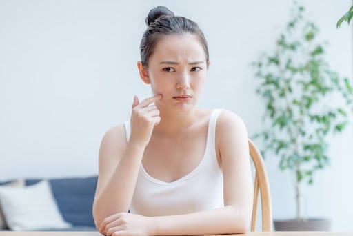 頬を触り険しい表情の女性