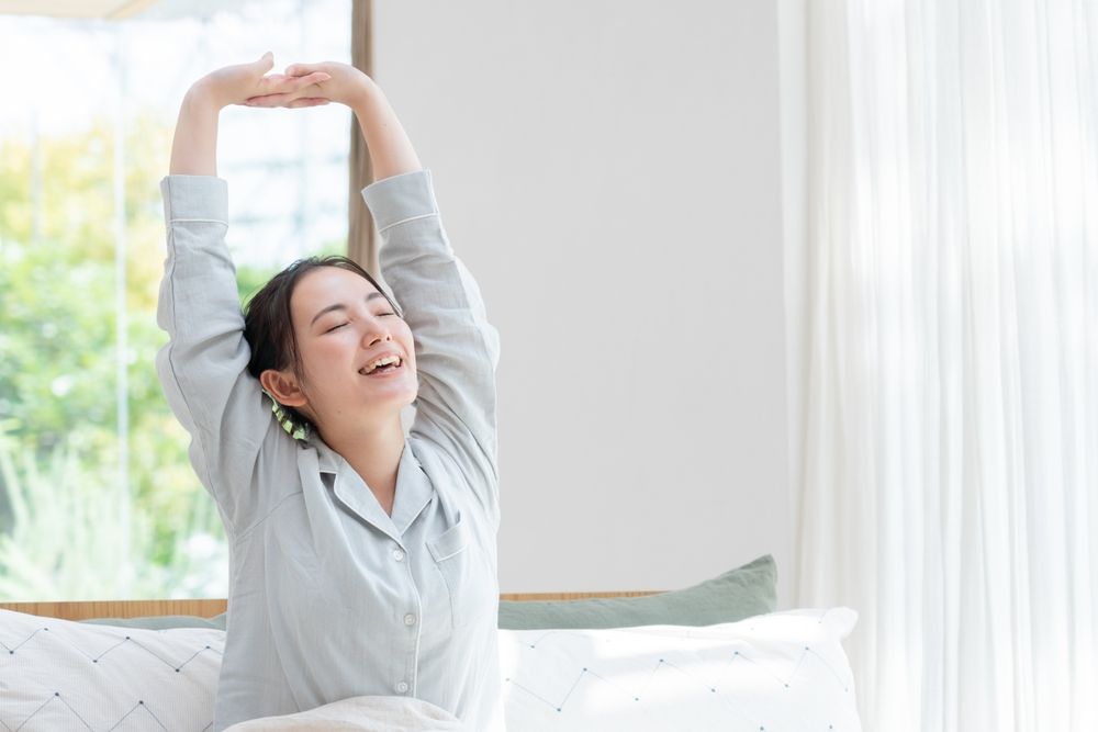 ベッドでストレッチをする女性