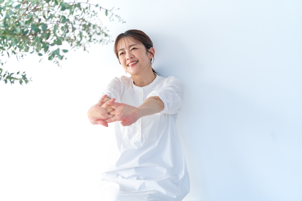 壁にもたれかかり手を伸ばす女性